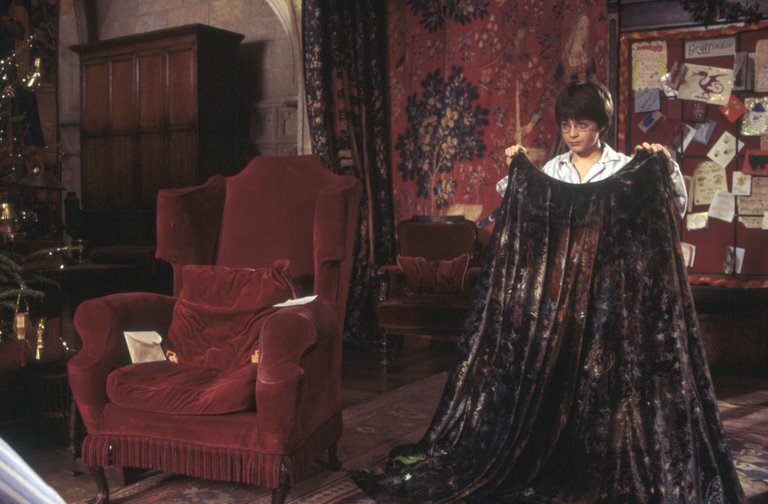 HarryPotter_WB_F1_HarryHoldingInvisibilityCloakInGryffindorCommonRoom_Still_100615_Land.jpg