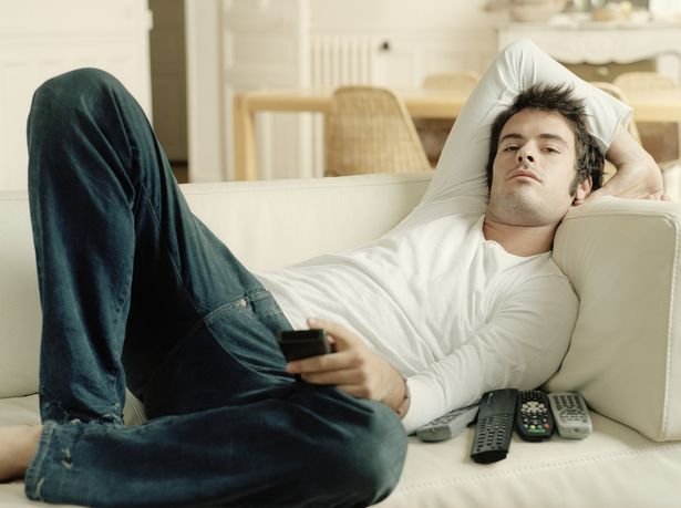 Man-relaxing-on-sofa-holding-remote-controls.jpg