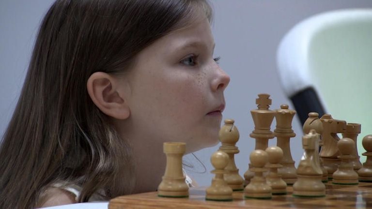 little-girls-face-next-to-chess-pieces.jpg