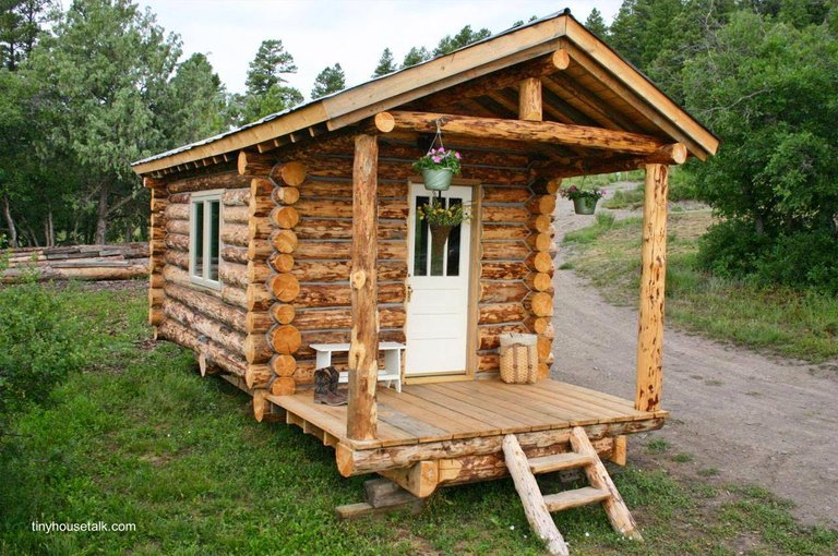 Pequeña cabaña de troncos rústicos apoyada sobre el suelo.jpg