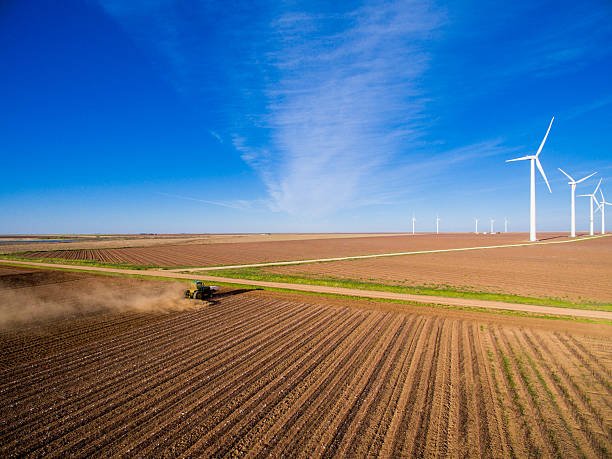 tractor-plowing-field-with-wind-turbinel-farm-in-the-distance-picture-id520611594.jpg