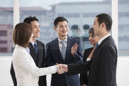 22365599-business-people-shaking-hands-with-a-team-of-colleagues-around-them.jpg