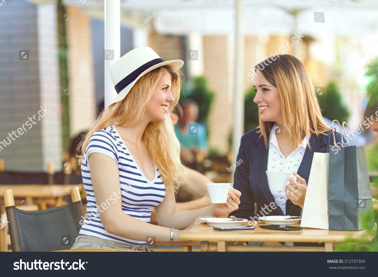 stock-photo-two-young-girlfriends-sitting-in-a-cafe-drinking-coffee-and-chatting-after-shopping-312737309.jpg