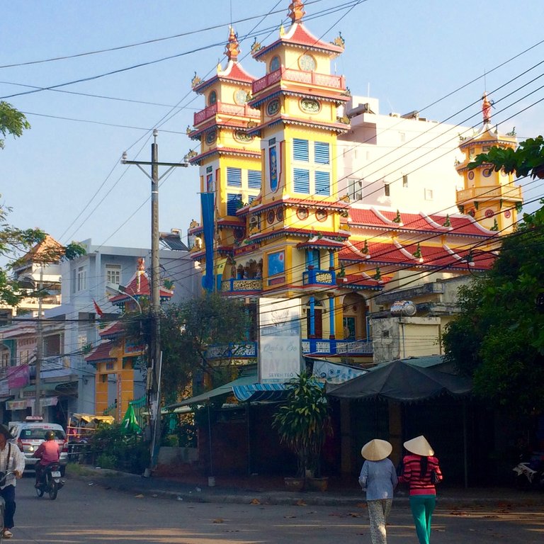 6 Two ladies wearing traditional Vietnamese Non La hats walk past the temple .jpg