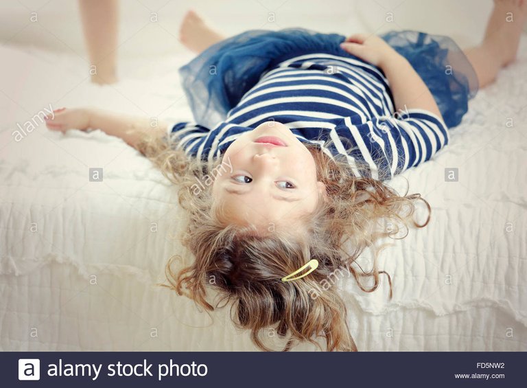 image-of-a-little-girl-laying-on-her-bed-with-her-head-hanging-off-FD5NW2.jpg