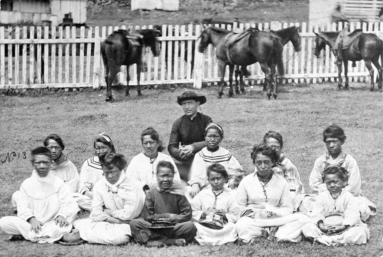 Father_Damien_with_the_Kalawao_Girls_Choir,_at_Kalaupapa,_Molokai,_circa_1878.jpg