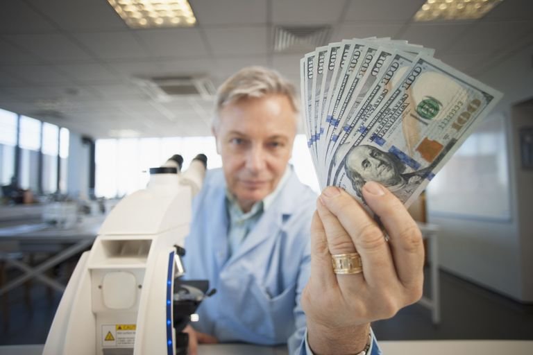 caucasian-scientist-holding-wad-of-money-in-lab-500046067-578156663df78c1e1f26e08b.jpg