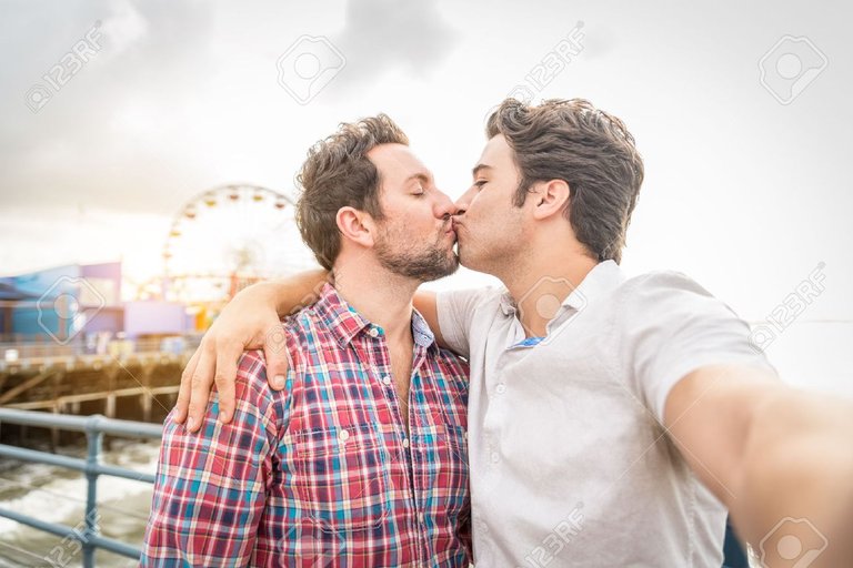 50576547-homosexual-couple-kissing-at-sunset-while-taking-a-selfie-Stock-Photo.jpg