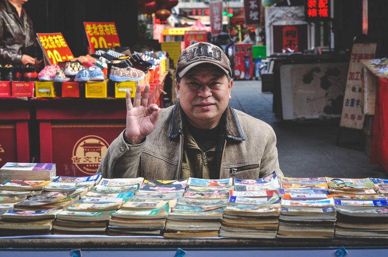 109.An old Chinese uncle selling tiny storybooks in the middle of the street, Tianjin, China..jpg