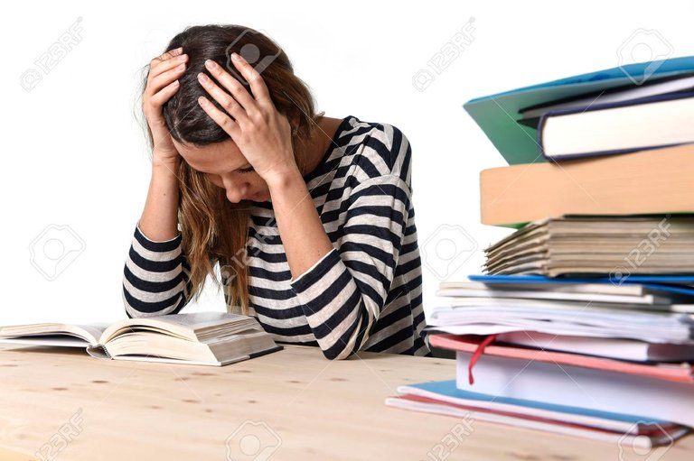 36900502-young-stressed-student-girl-studying-pile-of-books-on-library-desk-preparing-mba-test-or-exam-in-str.jpg