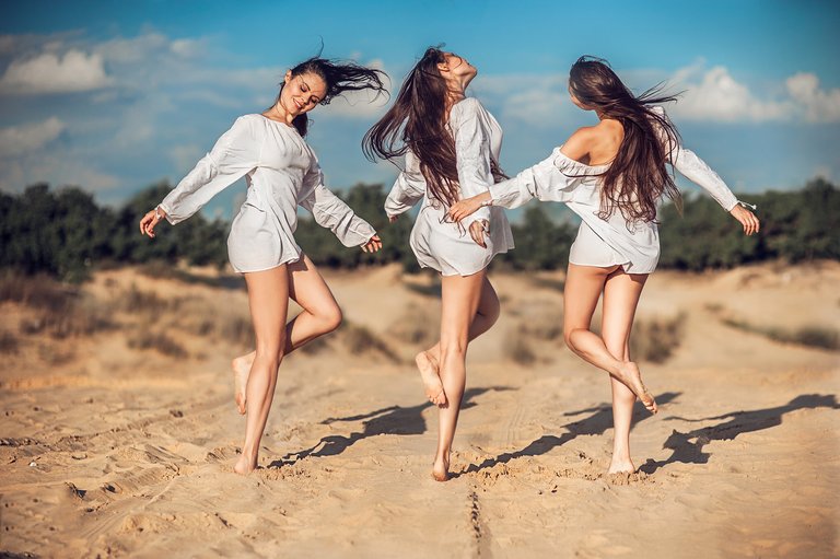 three-beautiful-girls-dancing-on-sandy-beach-in-sunlight.jpg