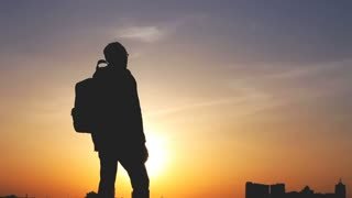 videoblocks-travel-concept-silhouette-of-a-man-with-a-backpack-against-bright-sky-sunset-sun-goes-down-cityscape-in-the-background-man-looks-ahead-raises-his-arms-up-holidays-advanture-trekking_s8j808klw_thumbnail-small01.jpg