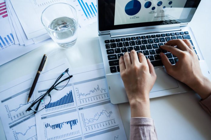 businessman checking reported profits on the paper and laptop.