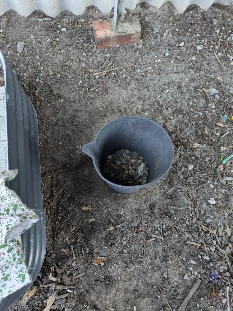 black bucket on dirt ground strewn with more gravel