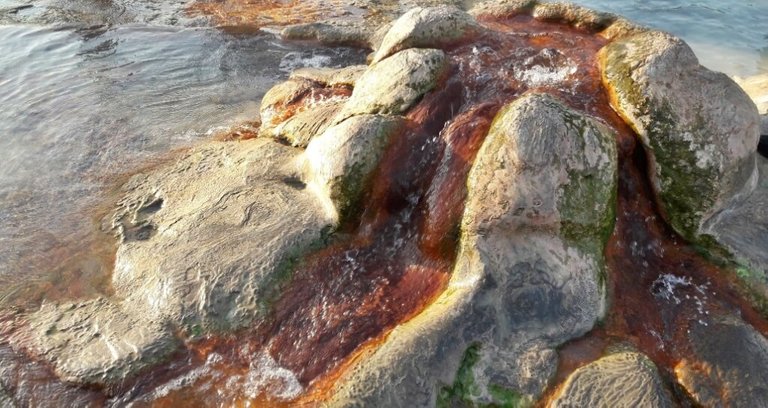 Rocky fountain-like structure in the middle with iron-rich water emanating from it