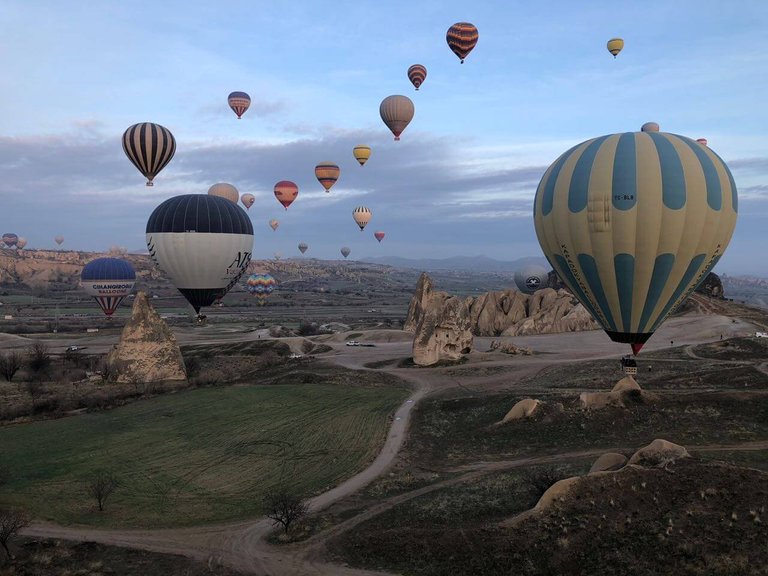 You see a cluster of volcanic rocks with other hot air balloons in the background