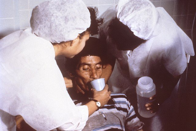 A cholera patient is drinking oral rehydration solution (ORS) in order to counteract his cholera-induced dehydration