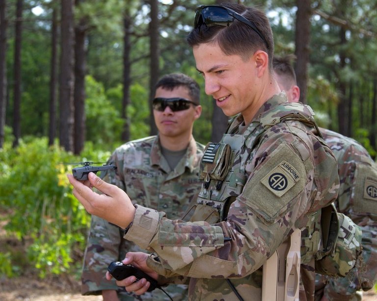 A solider with FLIR's black hornet mini-drone in hand
