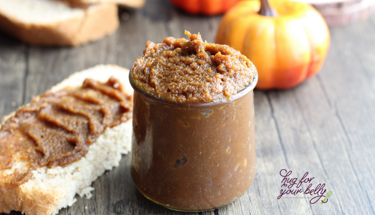 pumpkin butter in glass jar next to bread slice and pumpkin