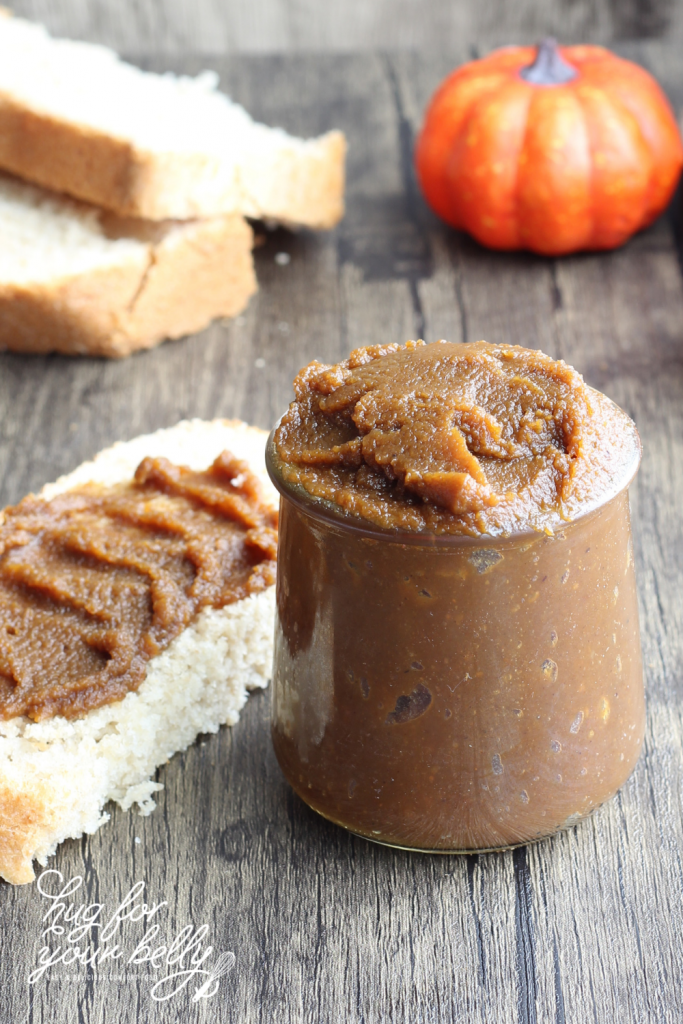 pumpkin butter in glass jar next to slice of bread and pumpkin