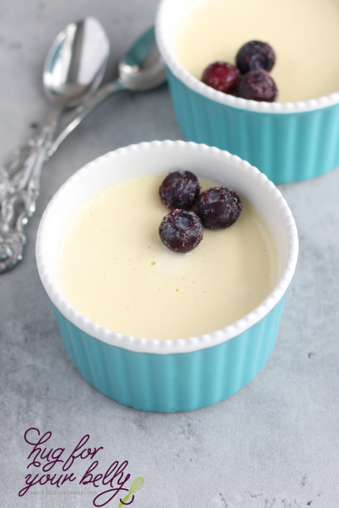 vanilla custard in blue dish with blueberries and dessert spoons