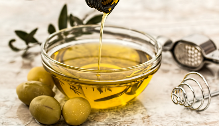 olive oil being poured into clear glass bowl