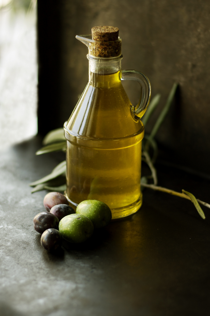 olive oil in bottle next to green and black olives