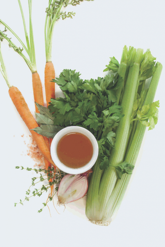 broth in cup surrounded by vegetables