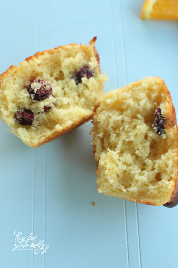 cranberry orange muffin cut in half on blue background