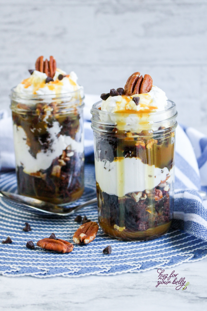 brownies in a jar topped with whipped cream and pecans