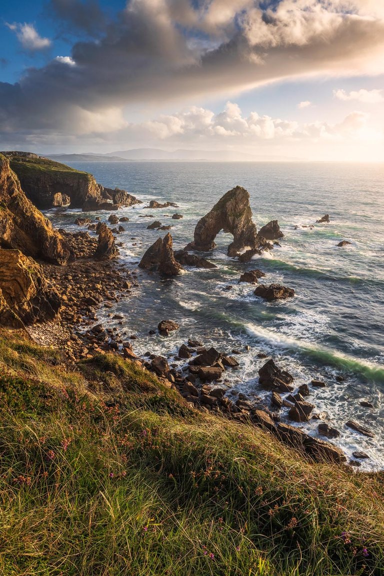 Dramatic cliffs and seastacks in golden light at Crohy Head.