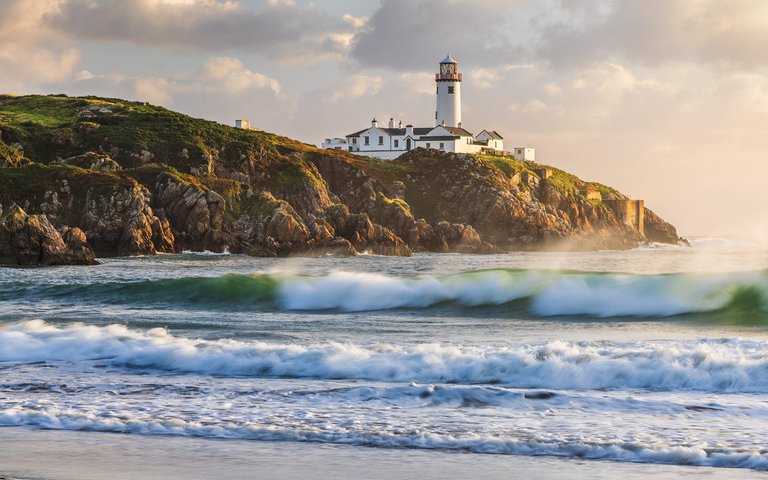 Unique Perspective of Fanad Head Lighthouse at sunrise from a nearby beach.