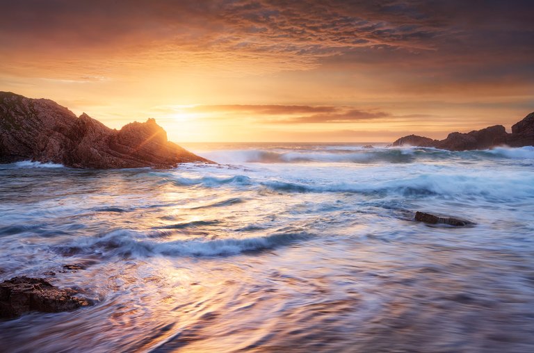 Waves crash on the shores of Murder Hole Beach during sunset.