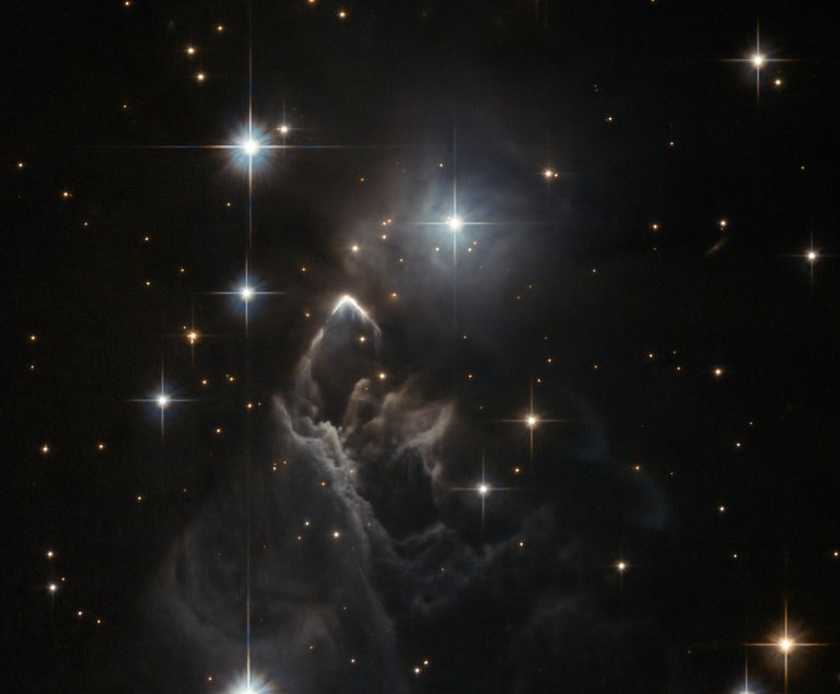 nebula IRAS 05437+2502 billows out among the bright stars and dark dust clouds that surround it in this striking image from the Hubble Space Telescope. It is located in the constellation of Taurus