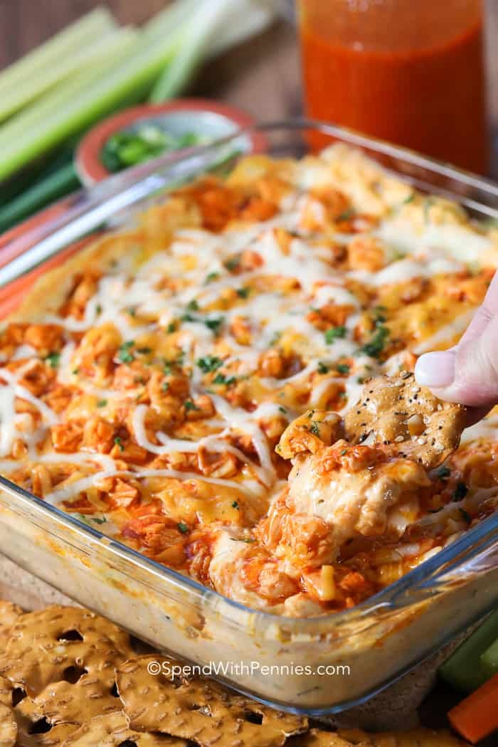 Scooping cheesy buffalo chicken dip with a pretzel cracker