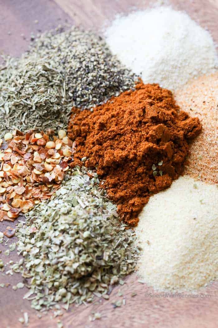 several piles of spices on a wood plate