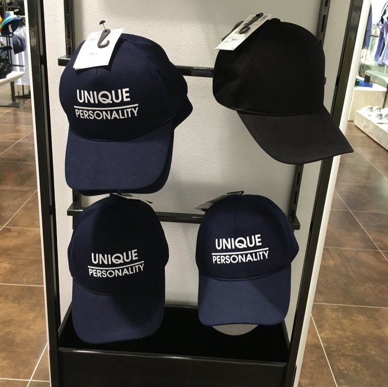 Blue baseball hats with white text: Unique Personality.