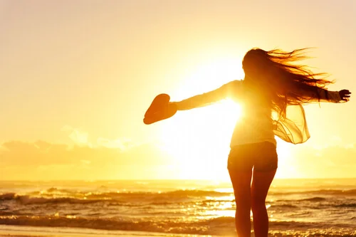 Mujer-con-un-corazón-en-la-mano-viendo-el-amanecer-en-la-playa.webp