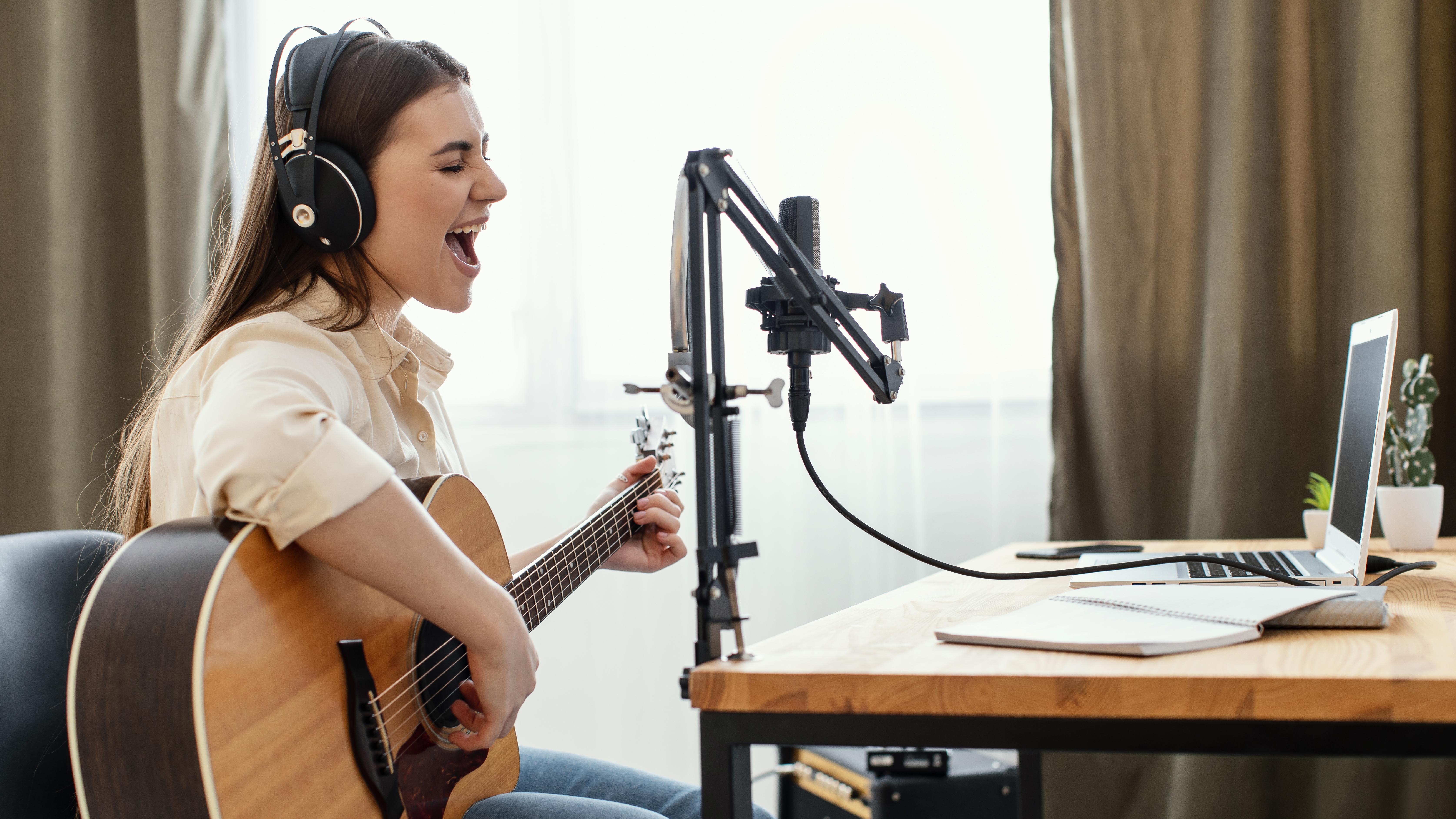 side-view-female-musician-recording-song-home-while-playing-acoustic-guitar.jpg