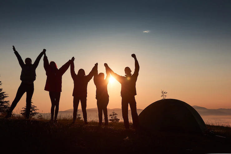 silhouette-group-people-have-fun-top-mountain-near-tent-during-sunset_146671-18472.webp