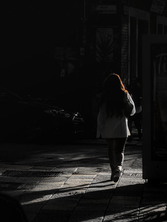 194832691-escena-callejera-no-saturada-con-una-silueta-de-mujer-caminando-en-una-calle-parcialmente-iluminada.jpg