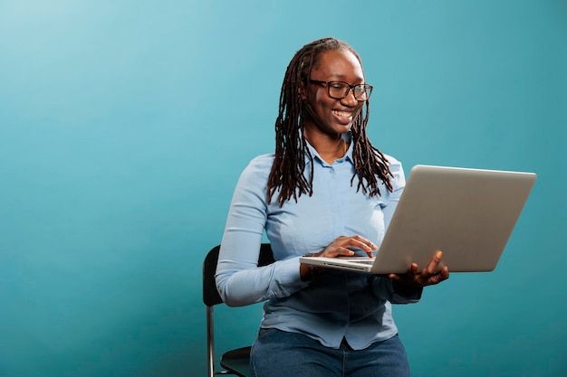 Free Photo _ Joyful pretty woman with portable modern computer standing on blue background while surfing web_ excited happy woman having laptop and smiling heartily while browsing webpages on internet.jpeg