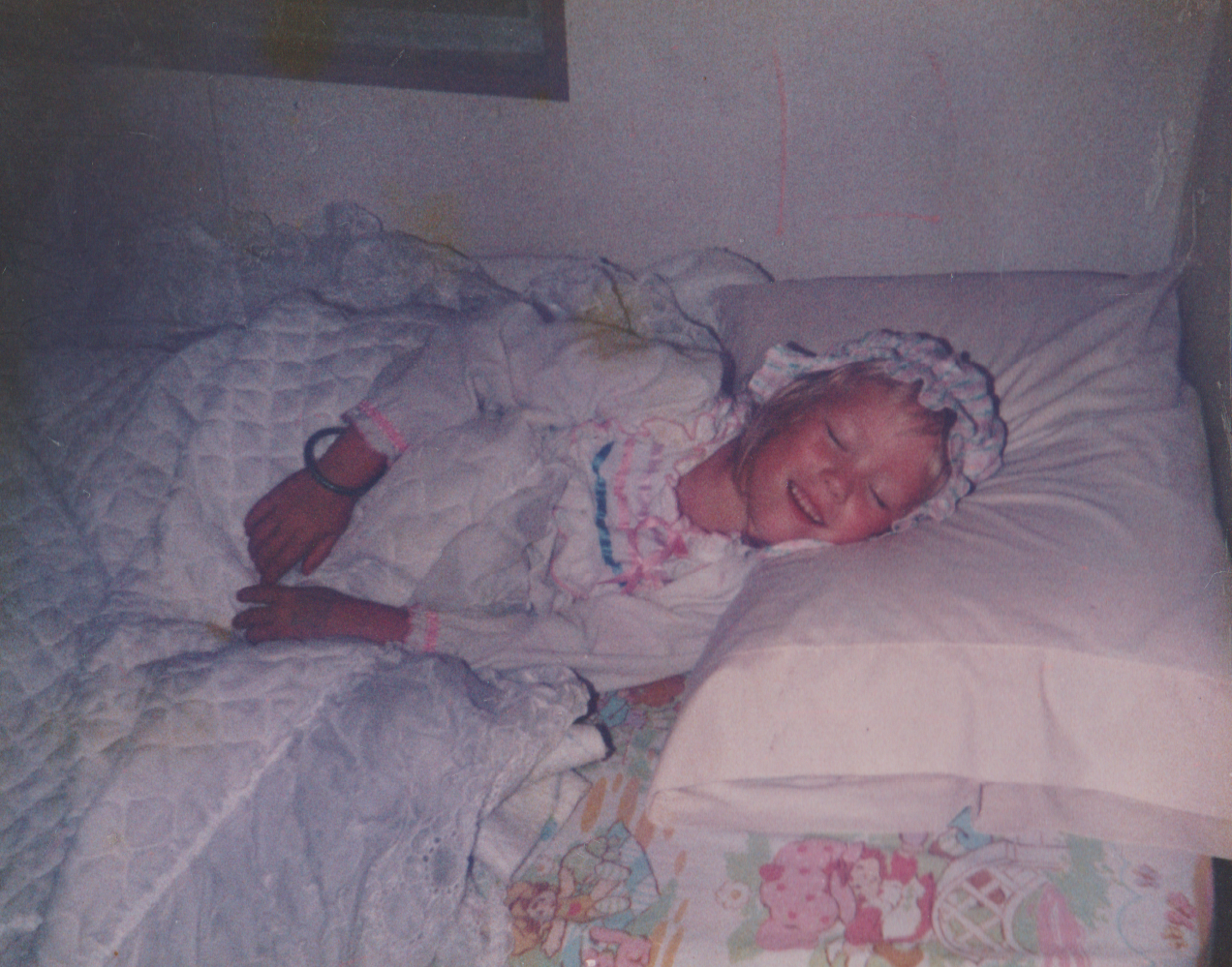 1987 maybe apx - Katie lying in bed in an outfit.png