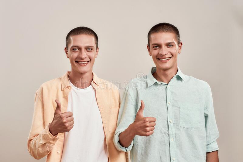 retrato-de-dos-jóvenes-hermanos-gemelos-felices-mostrando-pulgar-hacia-arriba-y-sonriendo-la-cámara-mientras-posan-juntos-204675600.jpg