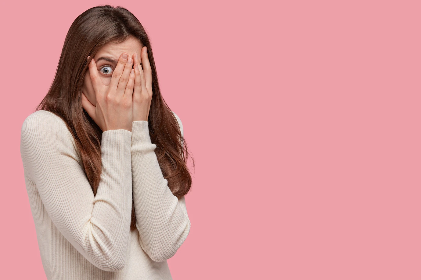 photo-scared-woman-covers-face-with-both-hands-looks-through-fingers-peeks-with-fear-has-dark-hair-dressed-comfortable-jumper_273609-24293.webp