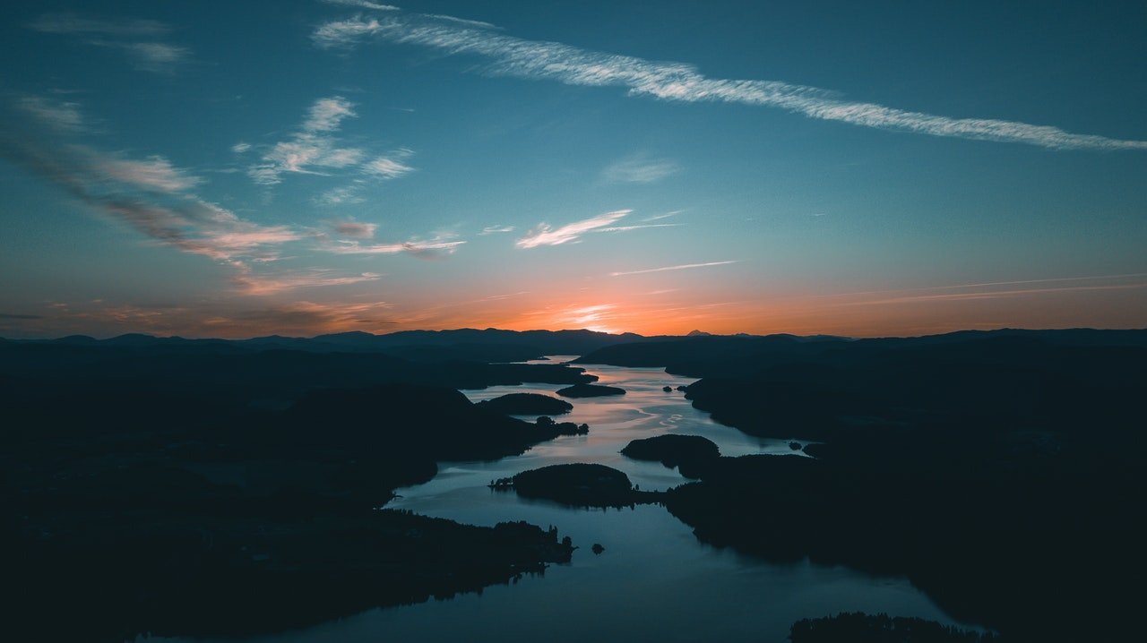 aerialphotographyofwaterbesideforestduringgoldenhour1144176.jpg
